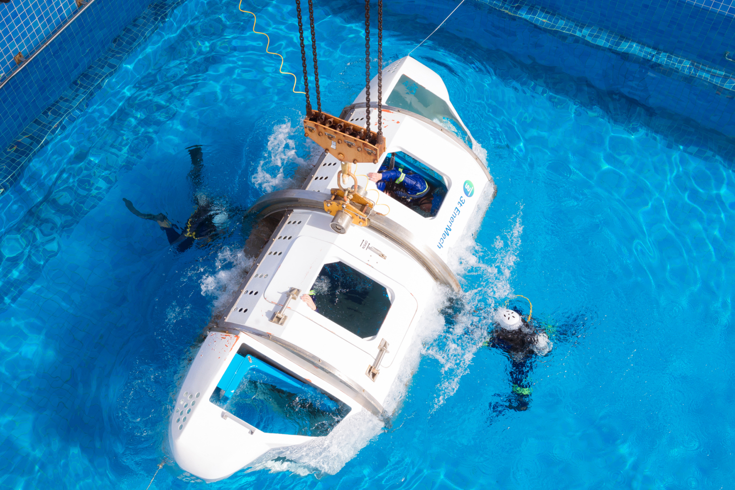 White helicopter body in swimming pool with two scuba divers on the outside. 