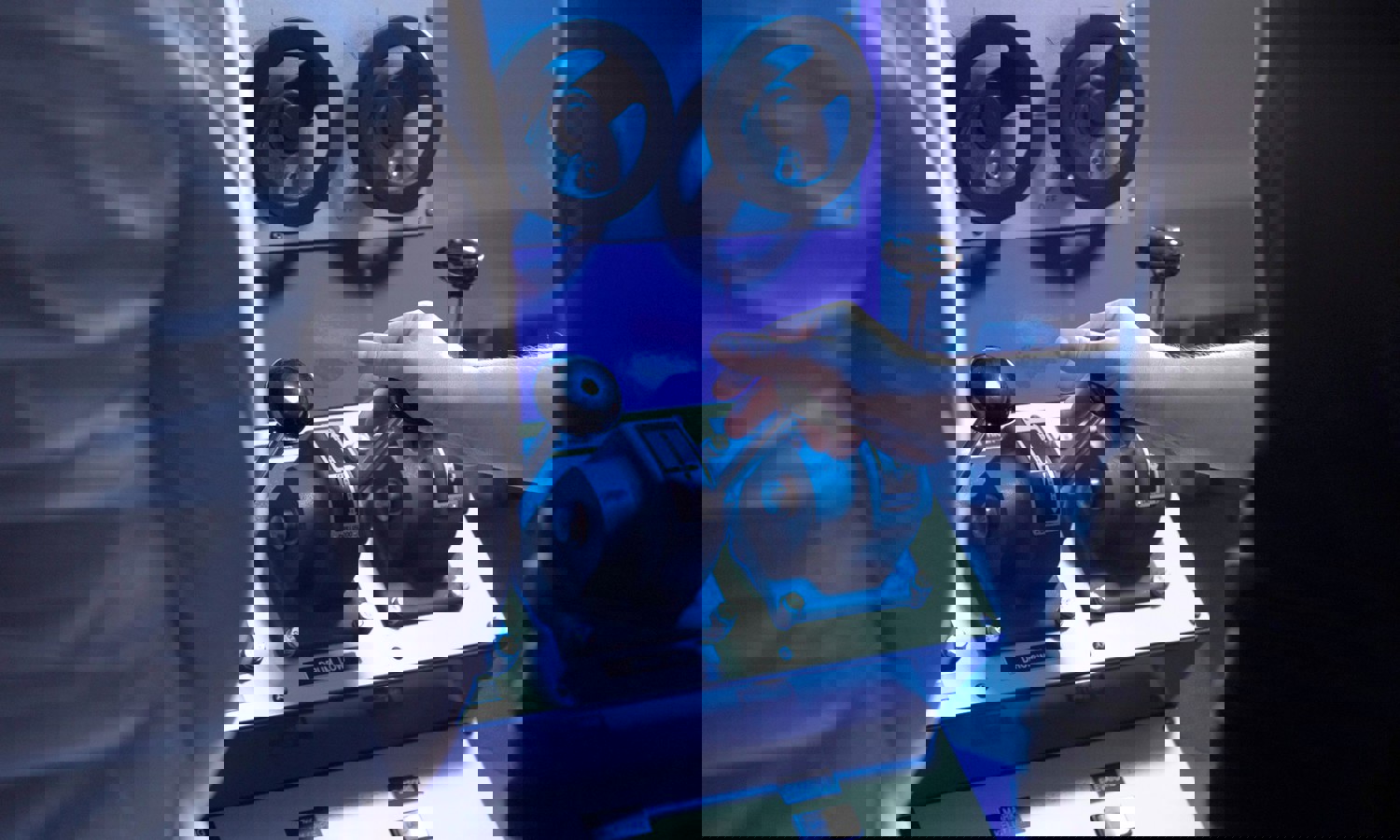 Two individuals operate a control panel with various levers and dials. One person's hand is shown gripping a lever.