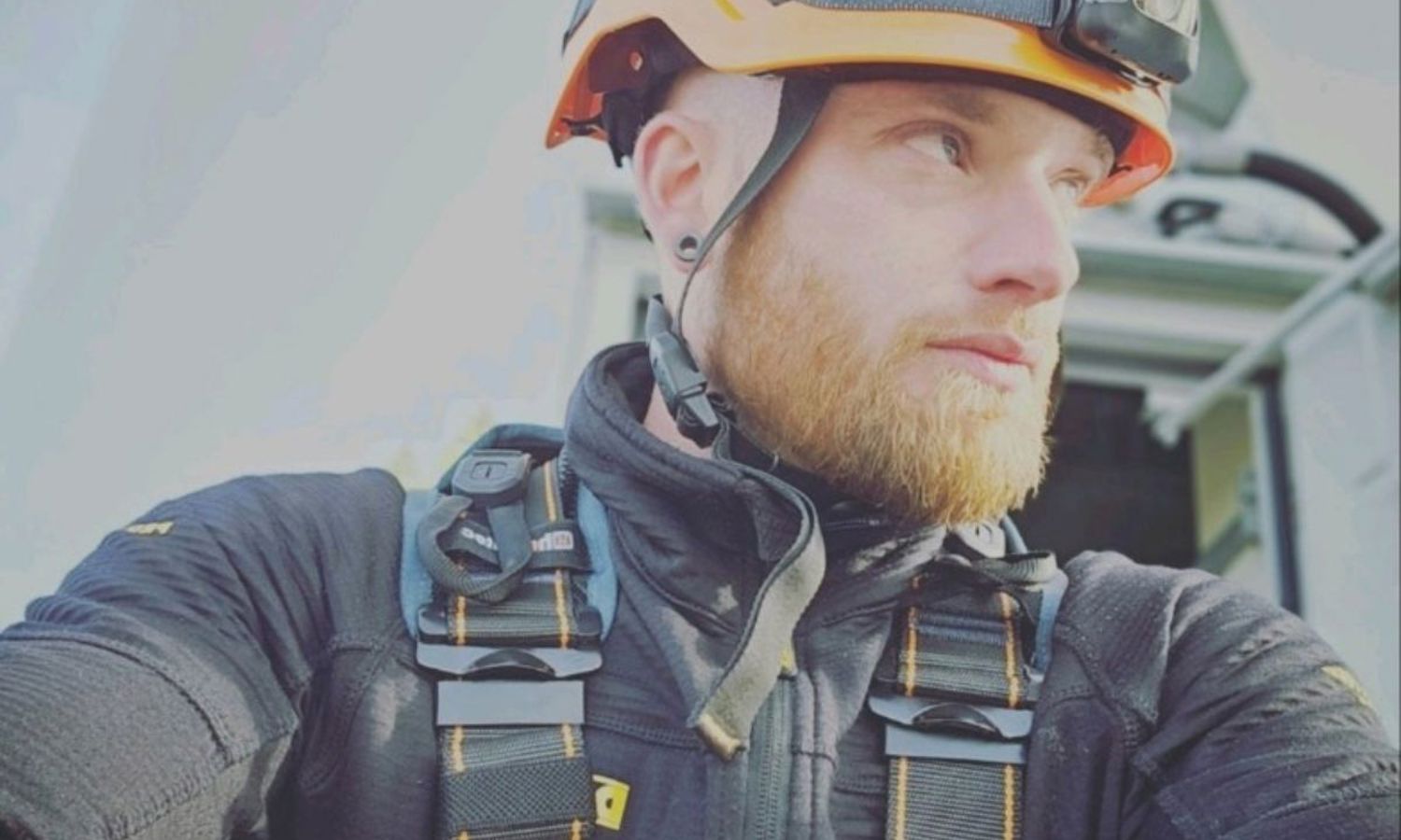 wind technician with an orange helmet and safety gear on.
