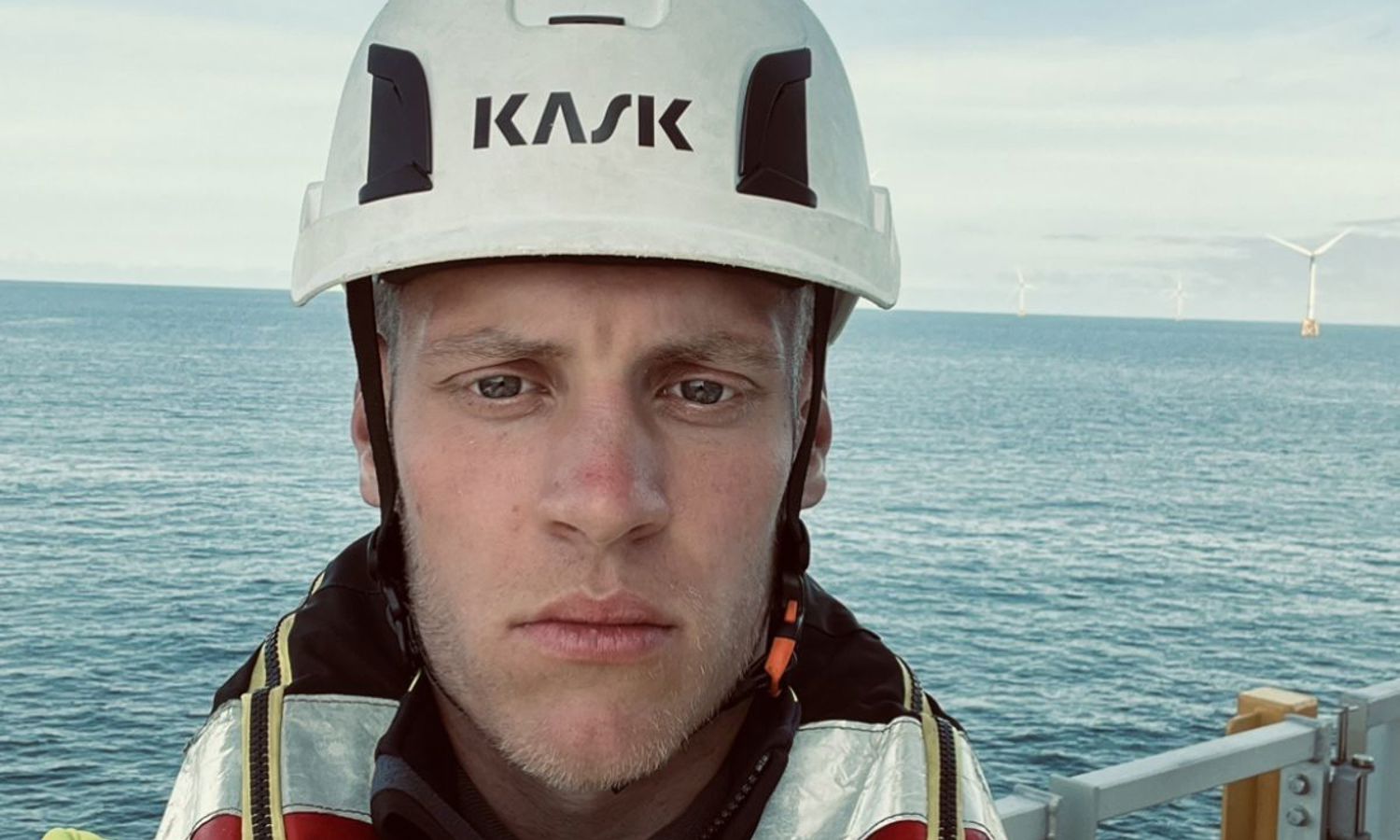 selfie of a man offshore with wind turbines