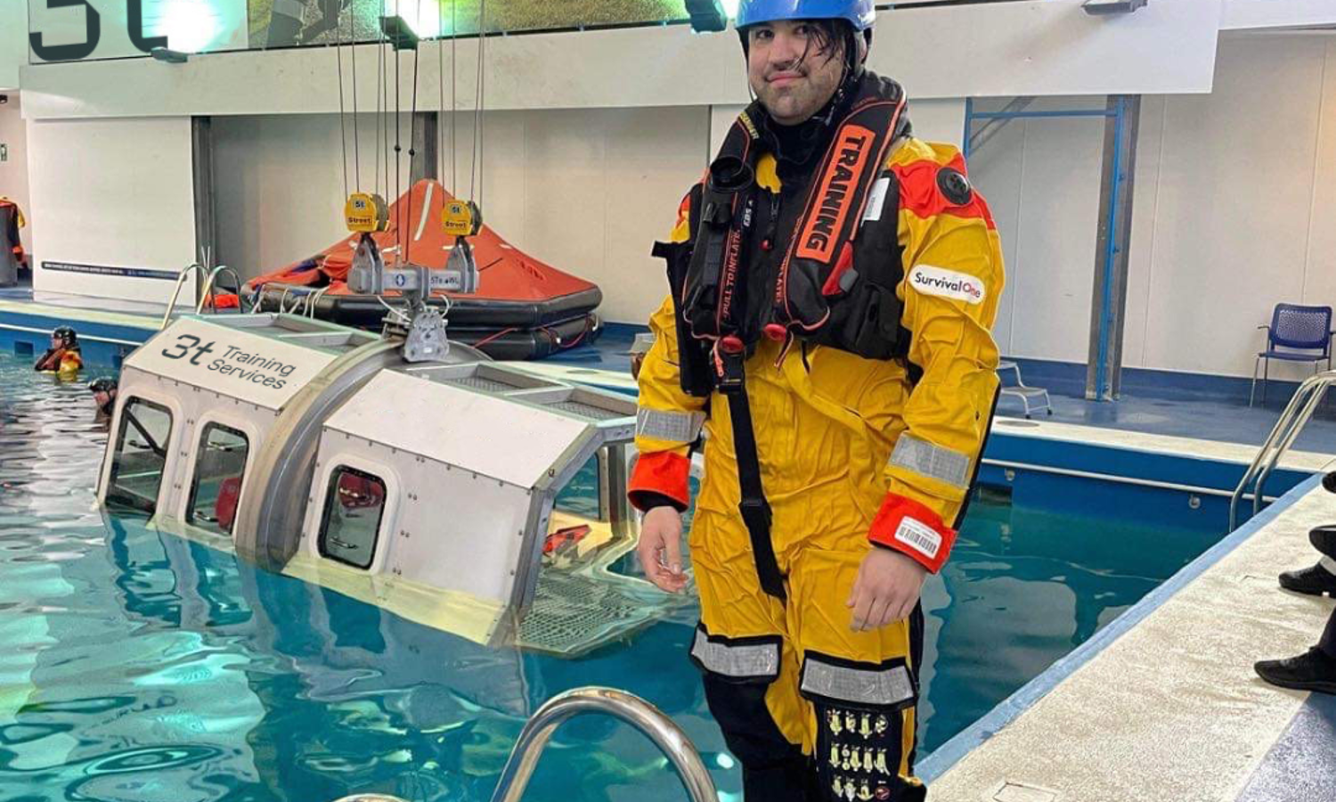 A person in yellow safety gear stands by a pool, overseeing a submerged training capsule, meticulously ensuring every aspect of the exercise is conducted safely.