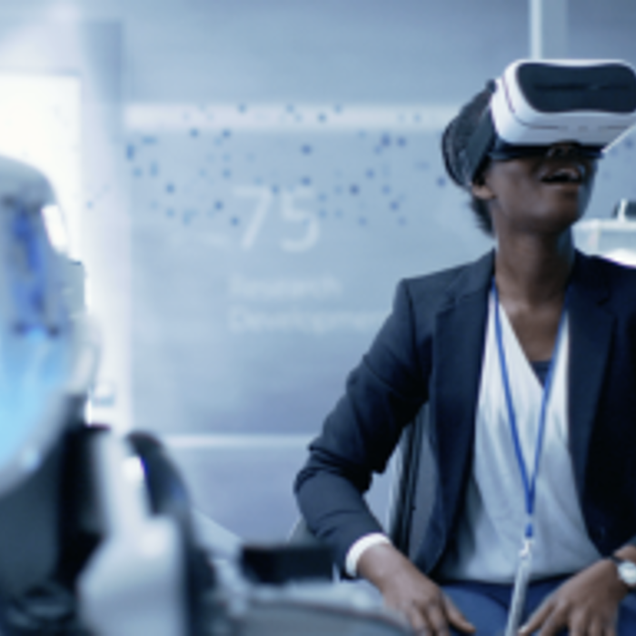 A person in a business suit is seated and wearing a virtual reality headset in a modern, high-tech environment.